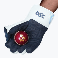 DSC Intense Speed adult wicketkeeping glove holding a red cricket ball against the dark grip palm